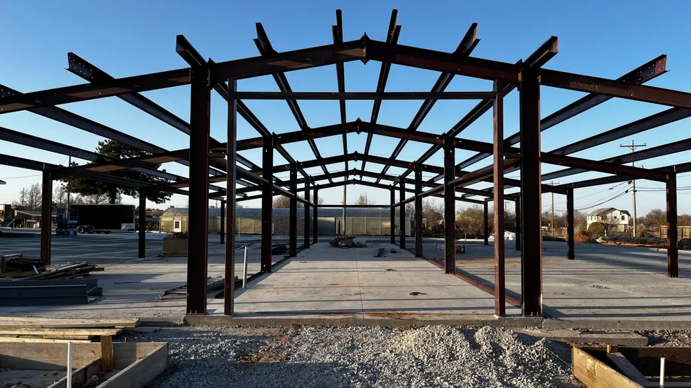 Red steel frame erected on a poured slab for a commercial building, seen from the open end