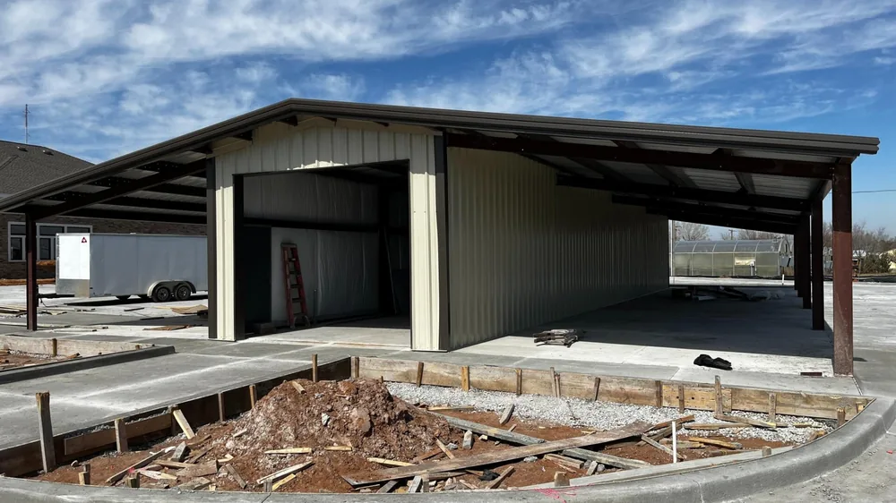 Olive steel building with wide open canopy bays and formed footings in the foreground