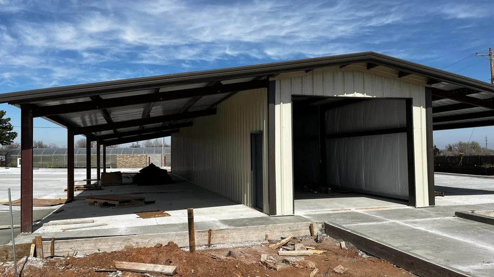 Steel building under construction with a wide covered canopy and open equipment bays
