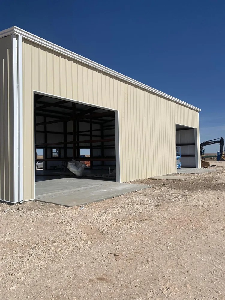 Cream steel shop building with two open bay doors on a rural site