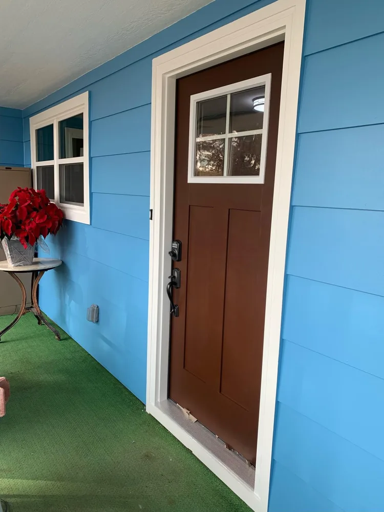 Newly installed stained wood entry door with a glass lite on a blue porch