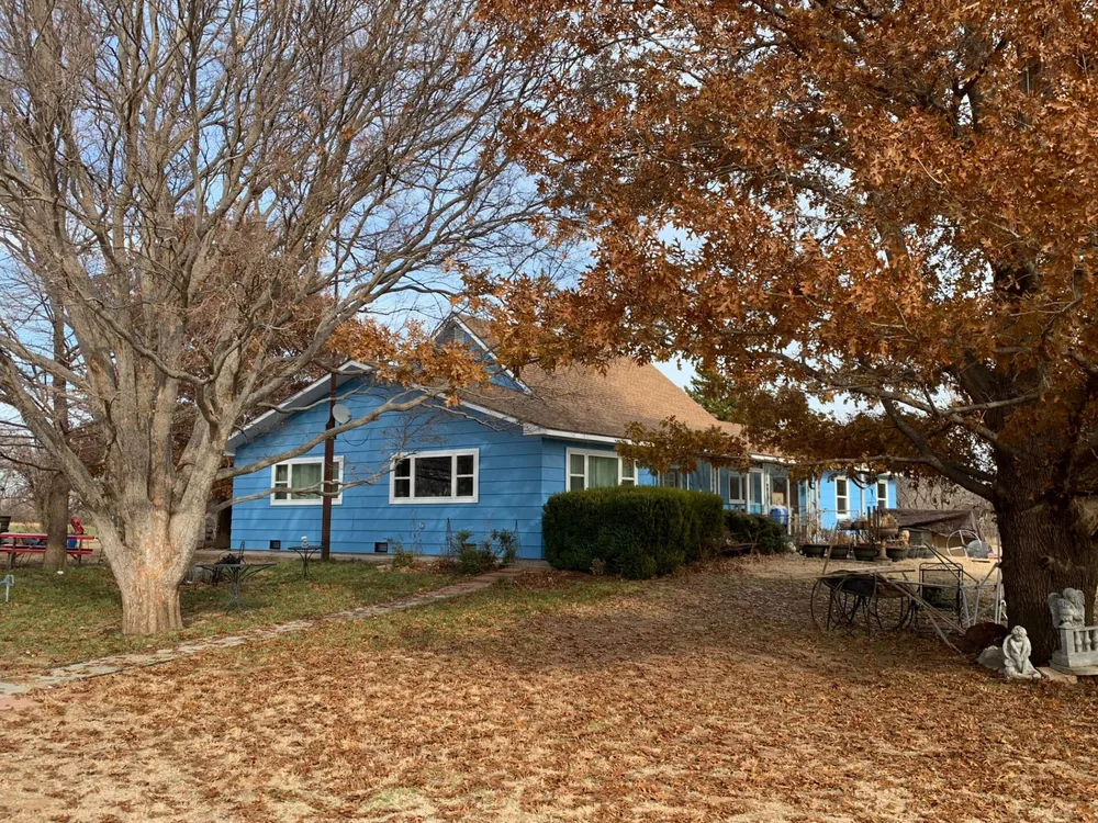 Blue house with fresh exterior paint framed by autumn oak trees
