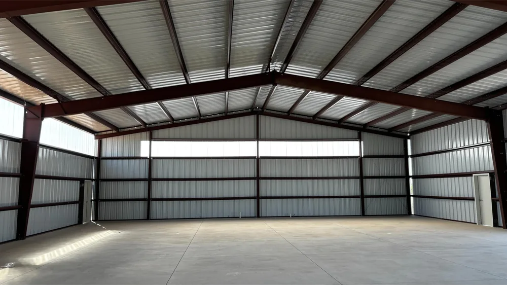 Bright open interior of a finished steel building lined with white wall panels