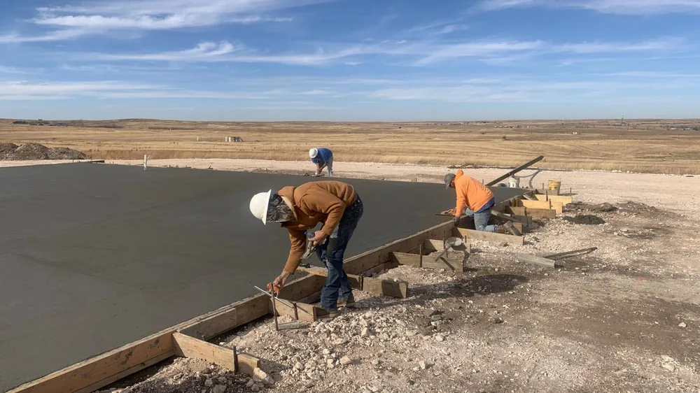 Workers screeding and finishing a freshly poured concrete slab