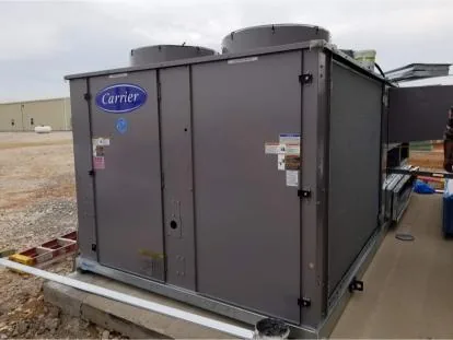 Carrier rooftop HVAC unit newly set and wired on a curb outside a metal building