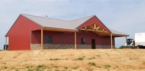 Completed red barndominium with a gabled entry porch and standing seam roof