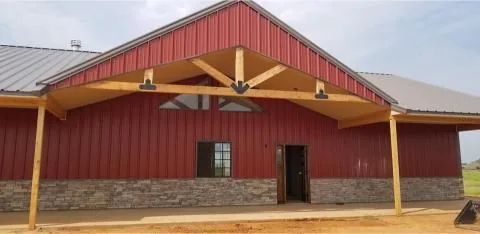 Timber truss gable entry with ceiling fans on a red metal home