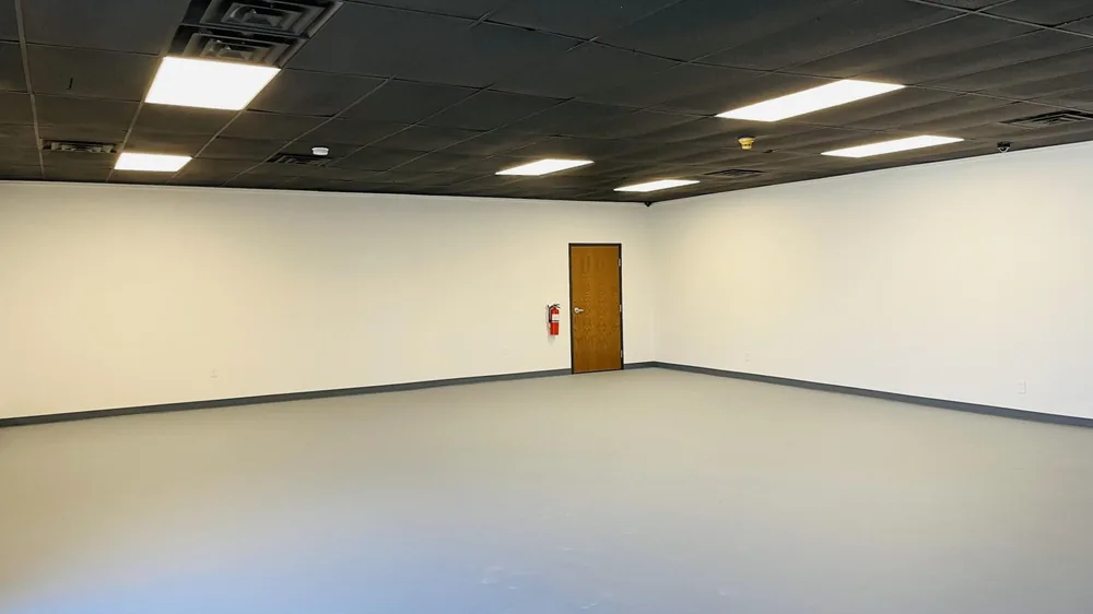 Newly finished room with recessed lighting, a wood door and a sealed grey floor
