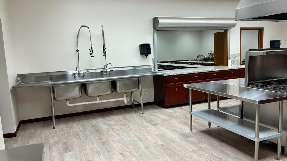 Commercial kitchen with a three-compartment stainless steel sink and stainless prep table
