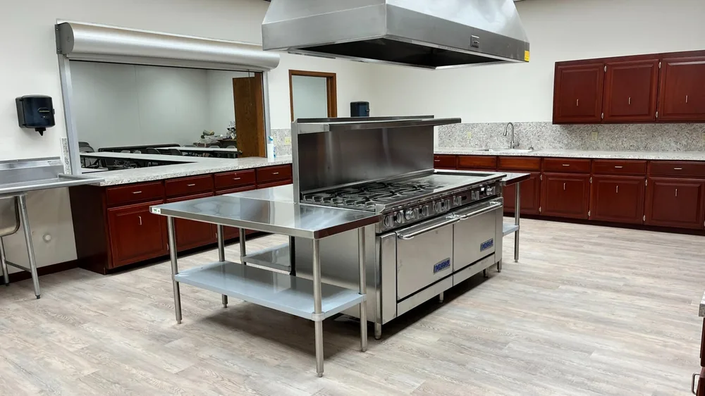 Commercial gas range on a stainless island beneath a new exhaust hood