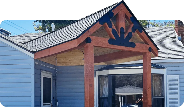 Newly built cedar-post porch gable with decorative timber trusses on a blue house