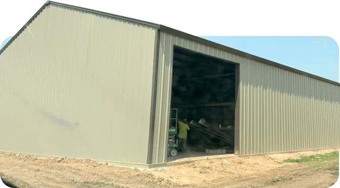 Long tan steel building with an open bay door and equipment stored inside