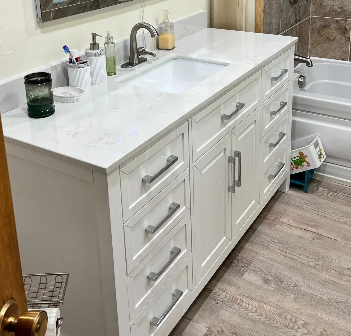 Remodeled bathroom with a white vanity, quartz countertop and undermount sink beside a new bathtub.